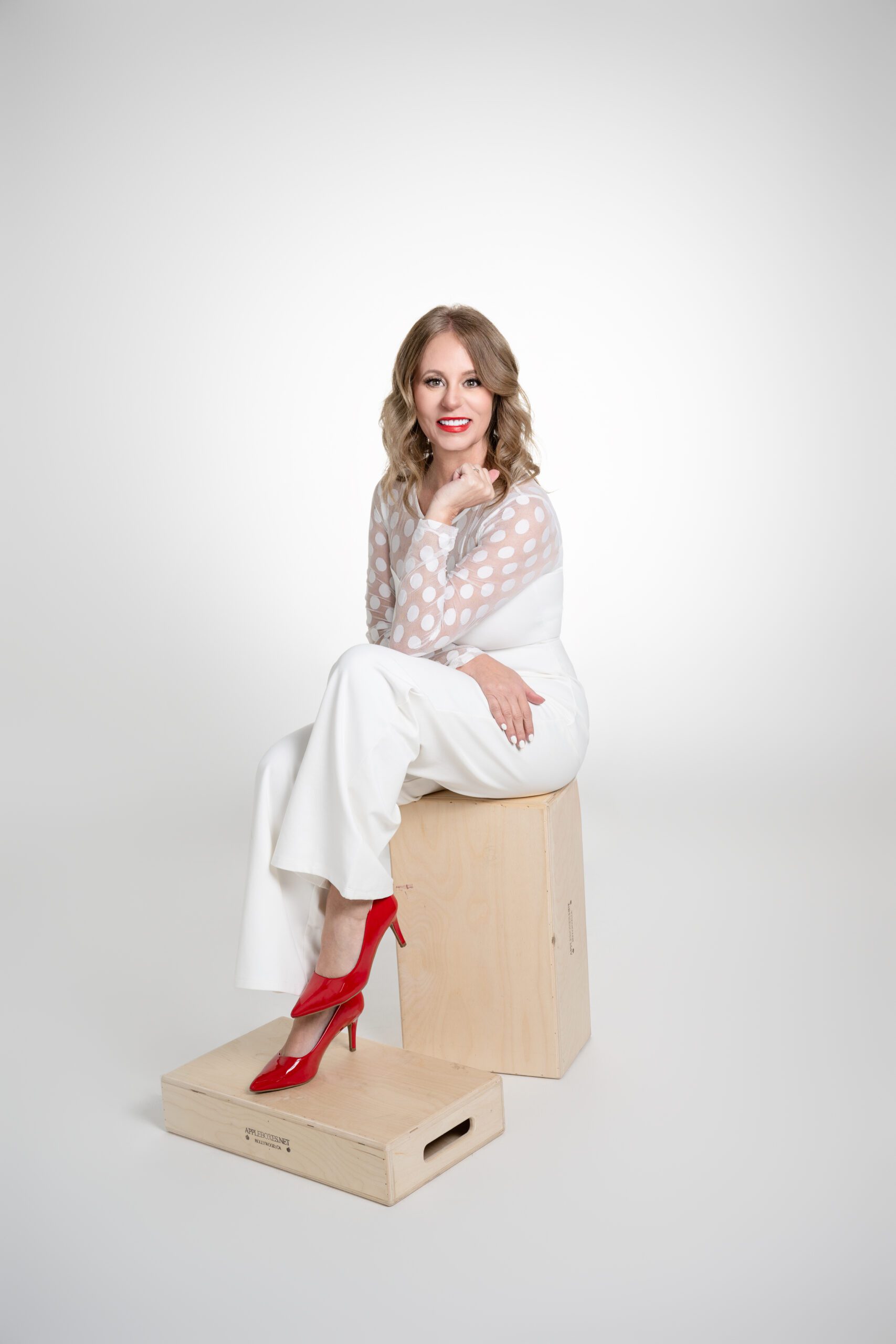 Professional business women sitting on stool with red shoes.