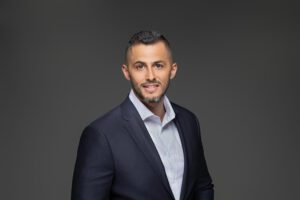 Professional headshot of Latino business man in front of grey background