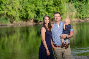 Family of three standing in front of river during summer